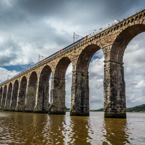 View of the train passing through the old stone bridge in Scotland